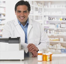 Male pharmacist at counter with medication.