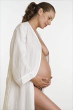 Studio shot of semi-nude pregnant woman in bathrobe.