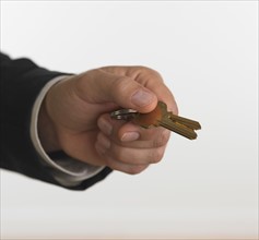 Studio shot of businessman holding keys.
