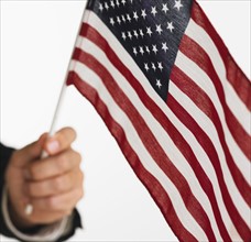 Close up studio shot of man holding American flag.