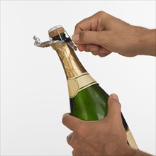 Close up studio shot of man opening champagne.