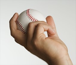 Close up studio shot of man holding baseball.