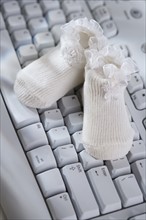 Close up of baby booties on computer keyboard.