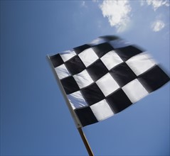 Checkered flag waving under blue sky.