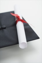 Close up of diploma and graduation cap.