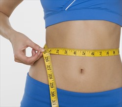Woman in athletic gear measuring waist.