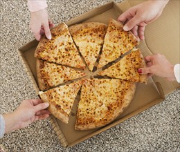 People talking slices of pizza from box.