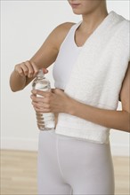Woman in athletic gear opening bottle of water.