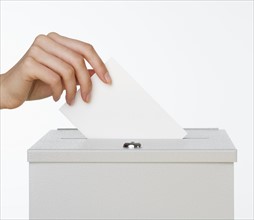 Close up of woman's hand putting card in box with slot.