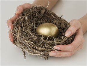 Close up of woman holding nest with golden egg.