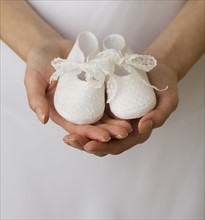 Close up of woman holding baby shoes.