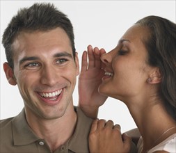 Woman whispering in man's ear.