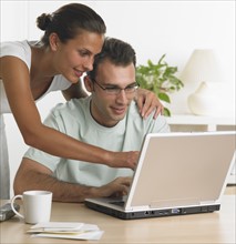 Couple using laptop at table.