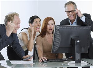 Group of businesspeople cheering with computer.
