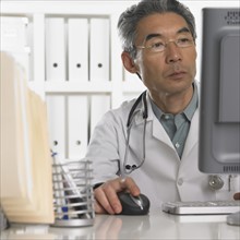 Senior male doctor using computer.