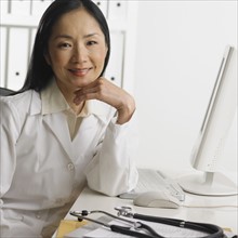 Female doctor sitting at computer smiling.