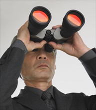 Businessman looking through binoculars.