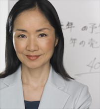 Asian businesswoman standing in front of white board.