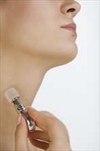 Close up of woman applying perfume to neck.