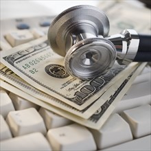 Close up of stethoscope on US Dollars and computer keyboard.
