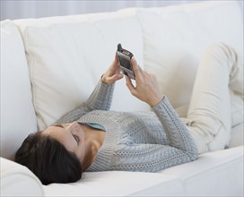 Woman laying on sofa using electronic organizer.