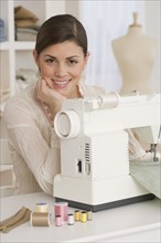 Portrait of woman next to sewing machine.