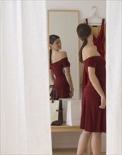 Woman in evening dress looking in mirror.