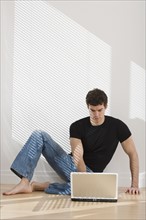 Man looking at laptop on floor.
