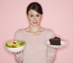 Woman holding salad and cake.