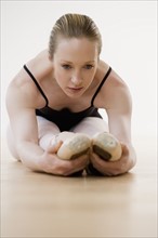 Female ballet dancer stretching on floor.