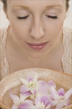 Woman smelling aromatherapy bowl with flowers.