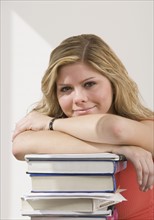 Woman leaning on stack of books.