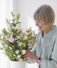 Senior woman arranging flowers.