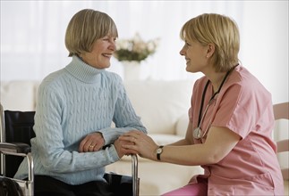 Nurse smiling at senior woman in wheelchair.