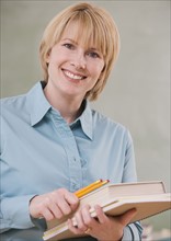 Woman holding school books and pencils.