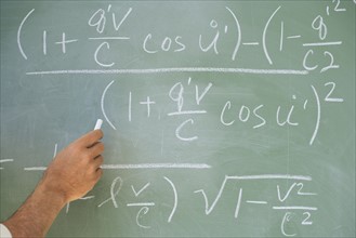 Professor writing formulae on blackboard.