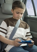 Boy playing video game in car.