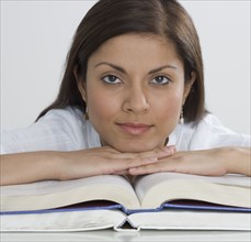 Indian woman leaning on open books.