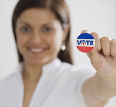 Indian woman holding up Vote pin.