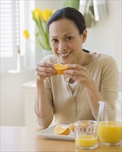 Asian woman eating oranges.