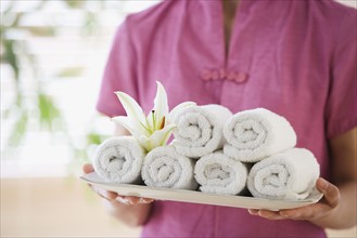 Woman holding tray of rolled towels.