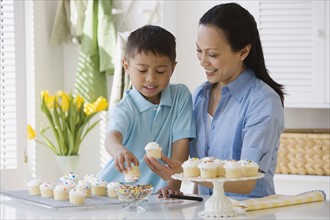 Asian mother and son decorating cupcakes.