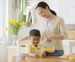 Asian mother pouring juice for son.