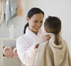 Asian mother drying son with towel.