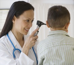 Asian female doctor examining boy’s ear.