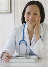 Asian female doctor with chart at desk.