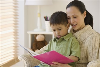Asian mother reading to son.