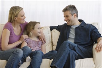 Family laughing on sofa.