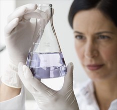 Female scientist looking at liquid in beaker.