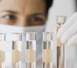 Female scientist looking at vials of liquid.